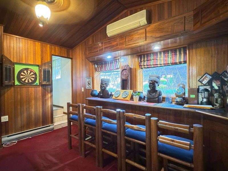 A dedicated bar area featuring extensive wood paneling, a built-in counter, leaded glass windows, and a split-system air conditioner.