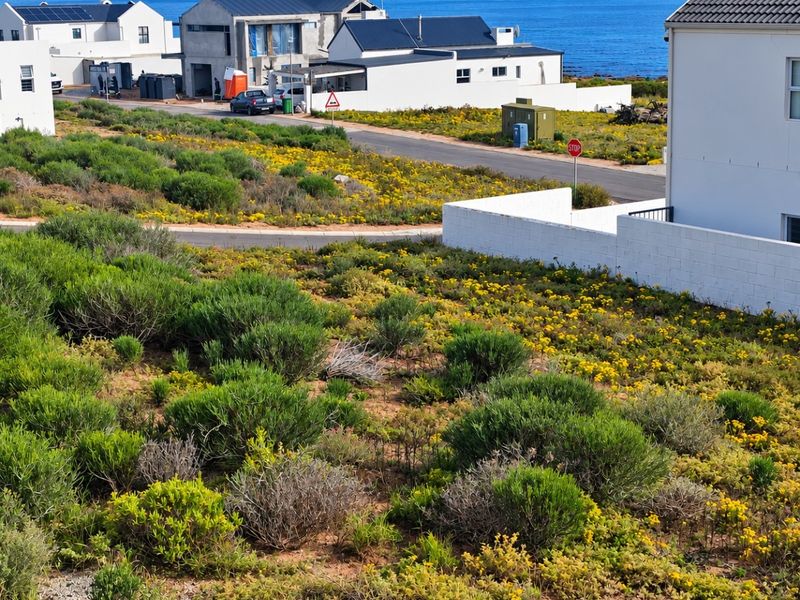 A scenic view of the coastal landscape and ocean from the residential plot, featuring surrounding neighborhood infrastructure and paved access roads.