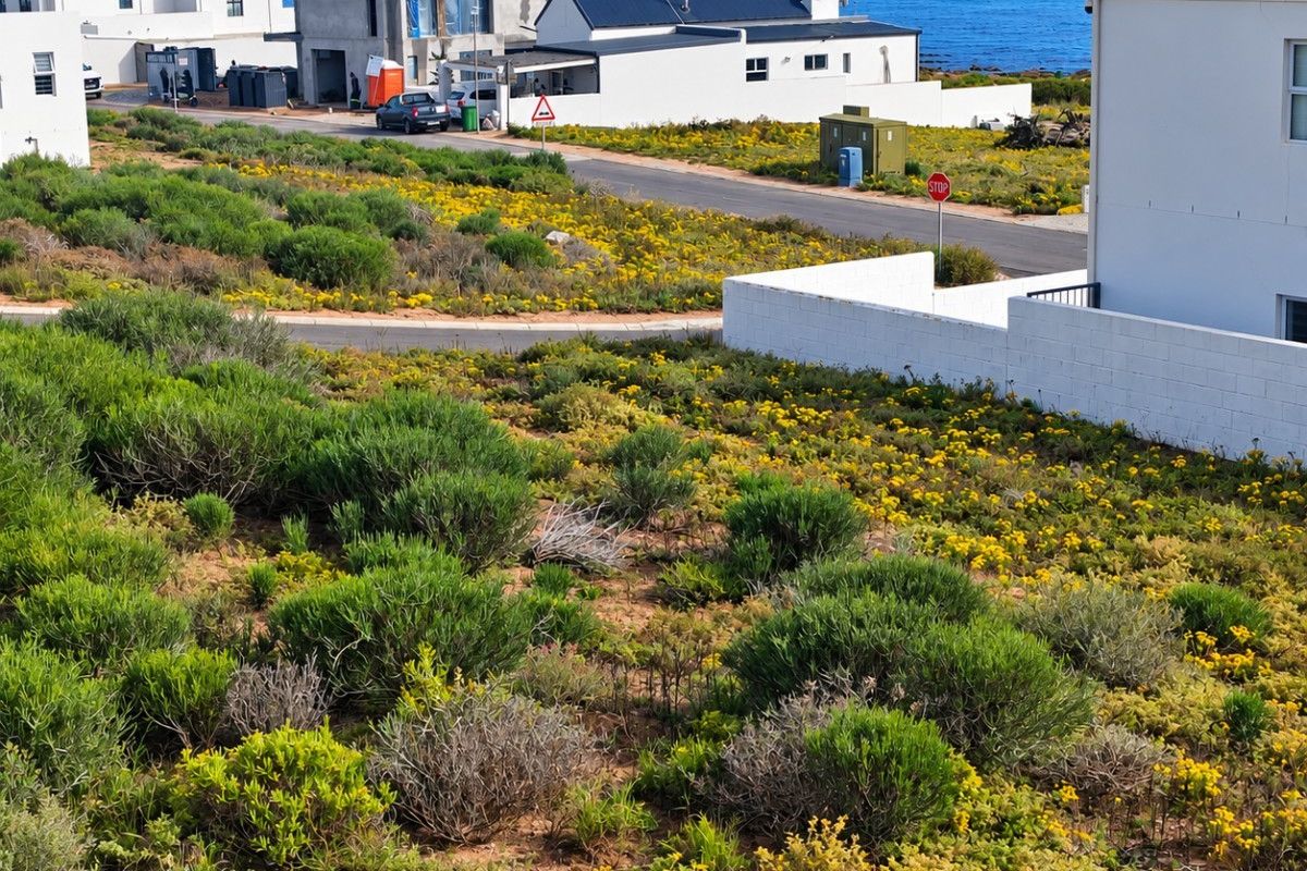 A scenic view of the coastal landscape and ocean from the residential plot, featuring surrounding neighborhood infrastructure and paved access roads.