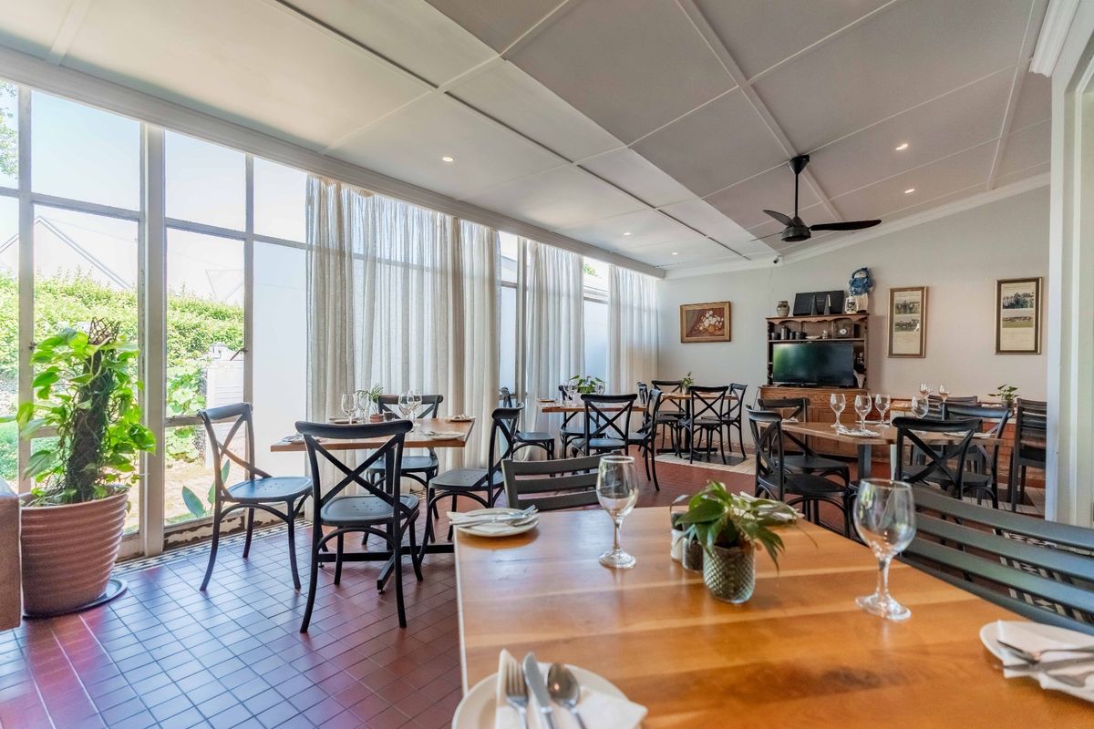 A bright and spacious living area featuring large glass windows, tiled flooring, and a coffered ceiling with a central fan.