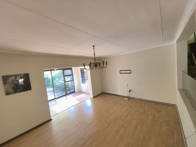 Spacious living area featuring laminate flooring, neutral walls, and a sliding glass door providing access to the outdoor area.