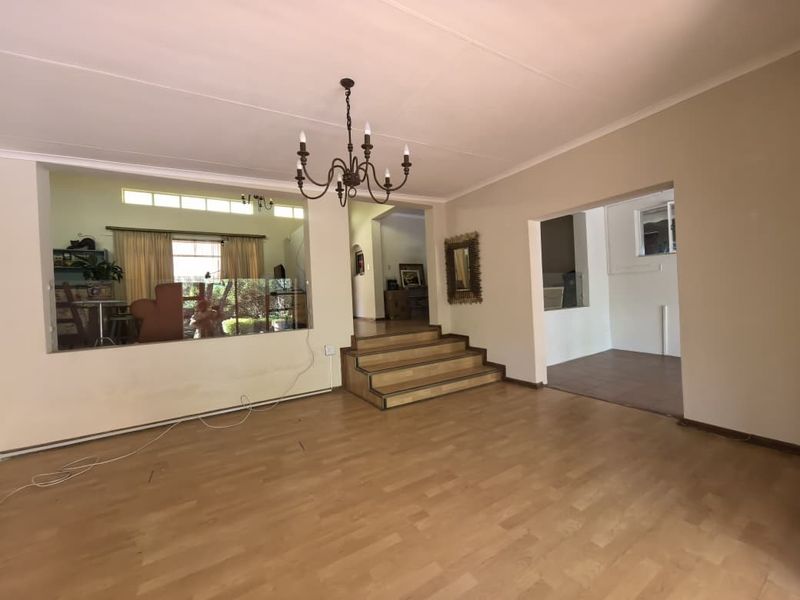 Spacious living area featuring laminate flooring, a raised platform section, and an interior window looking into an adjacent room.