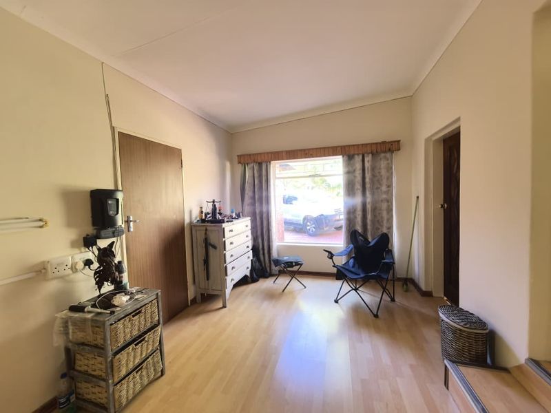 A living room featuring light-toned laminate flooring, neutral walls, and a large window providing natural light.