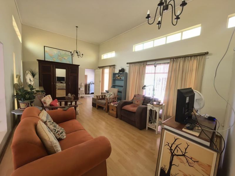 Spacious living room featuring high vaulted ceilings, clerestory windows for natural light, laminate flooring, and a classic wrought iron chandelier.