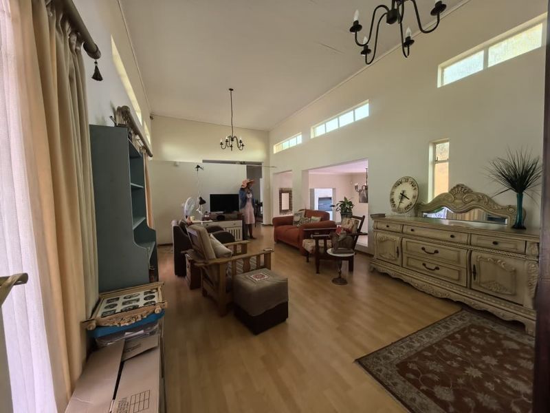 Spacious living area featuring vaulted ceilings, clerestory windows for natural light, and laminate flooring, offering a versatile open-plan layout.