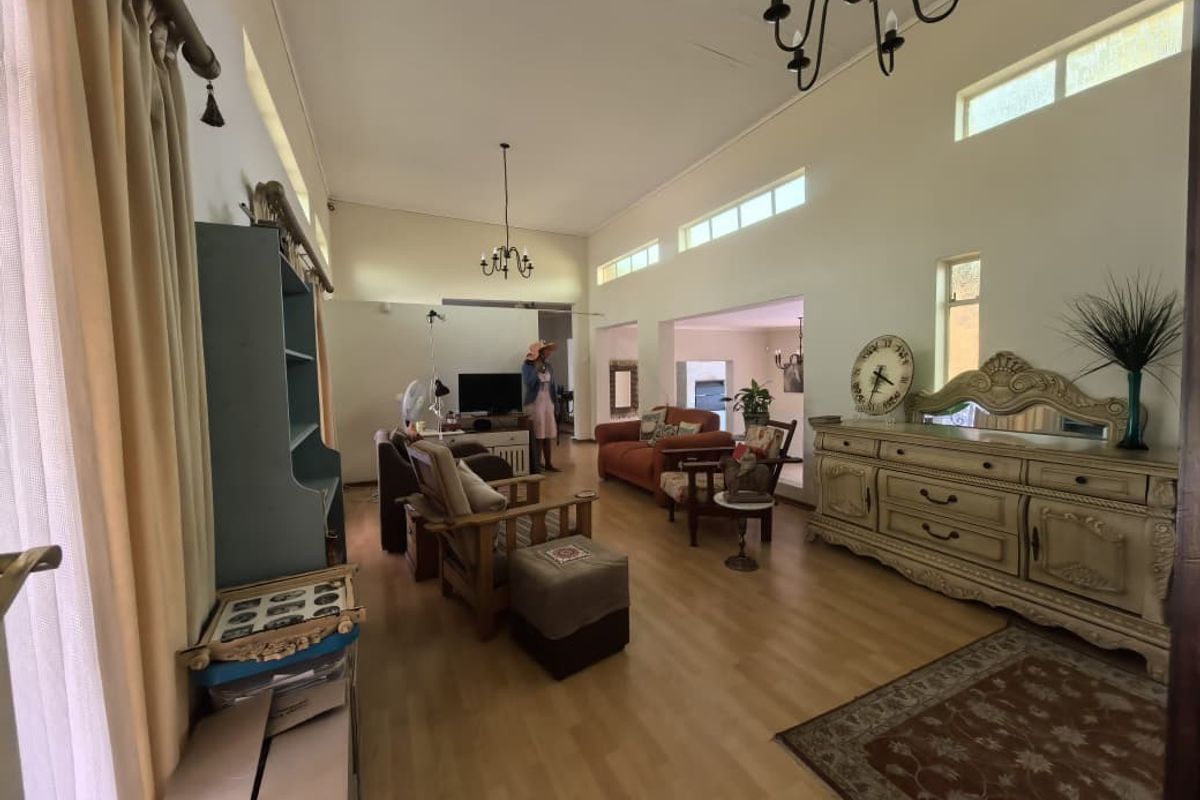 Spacious living area featuring vaulted ceilings, clerestory windows for natural light, and laminate flooring, offering a versatile open-plan layout.