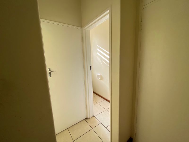 A simple interior hallway featuring tiled flooring and white internal doors, connecting different areas of the apartment.