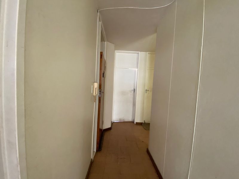A functional hallway featuring tiled flooring and an intercom system, providing access to multiple rooms within the apartment.