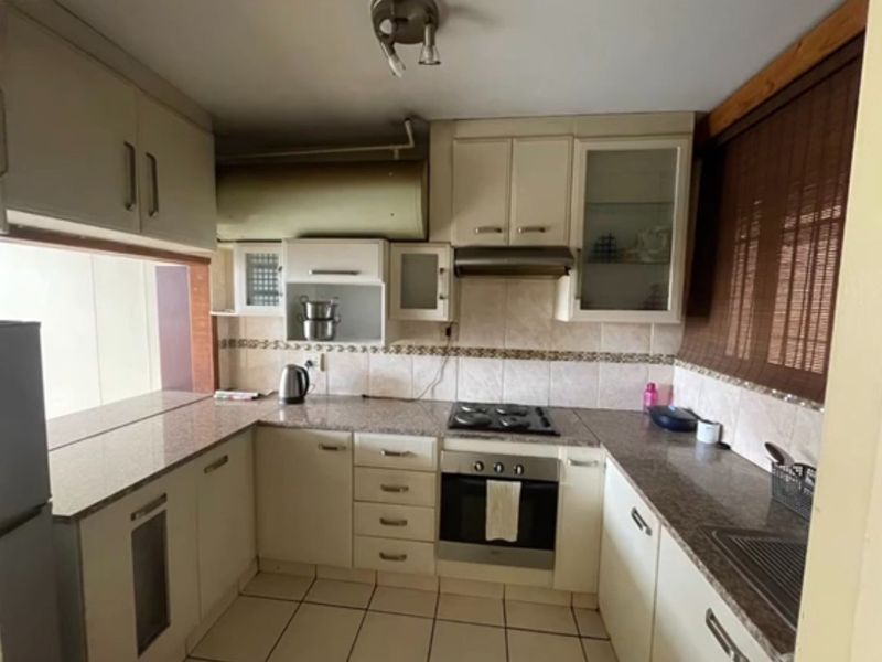 A functional kitchen featuring granite countertops, built-in cabinetry, a gas hob, and an integrated oven, offering a practical layout for daily meal preparation.