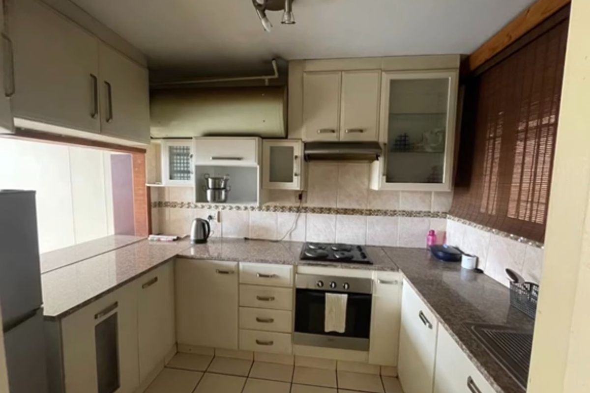 A functional kitchen featuring granite countertops, built-in cabinetry, a gas hob, and an integrated oven, offering a practical layout for daily meal preparation.