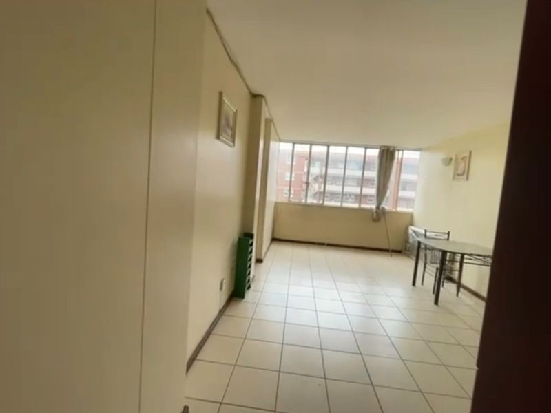 A spacious living area featuring tiled flooring and large windows, offering a bright and open layout ready for modernization and personal styling.