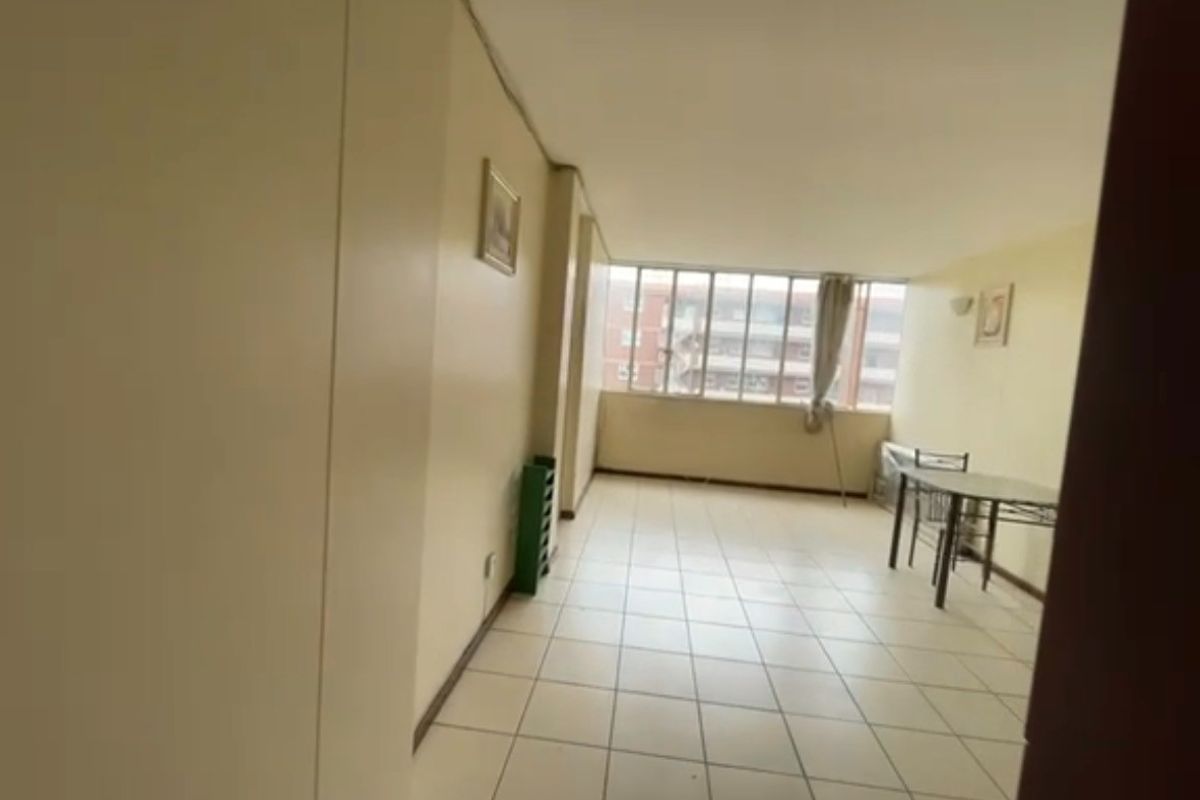 A spacious living area featuring tiled flooring and large windows, offering a bright and open layout ready for modernization and personal styling.
