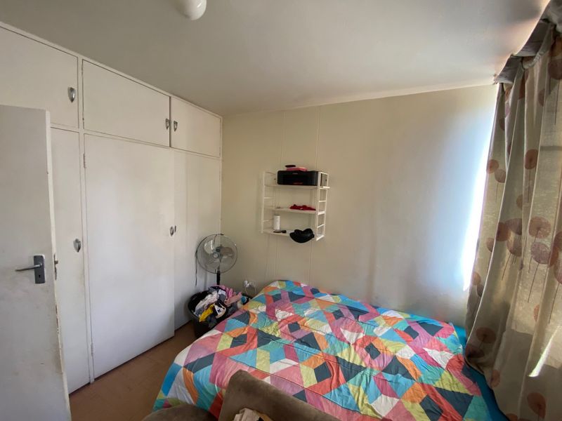 A bedroom featuring built-in cupboards and laminate flooring, offering a functional space with potential for cosmetic updates.