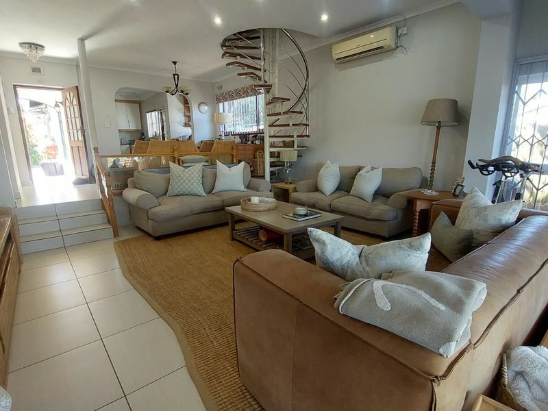 Spacious open-plan living area featuring a distinctive spiral staircase, tiled flooring, and integrated air conditioning, providing a functional and connected layout.