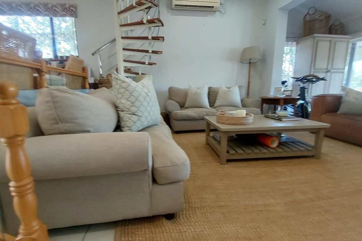 Spacious living area featuring a distinctive spiral staircase and wall-mounted air conditioning unit, offering a comfortable and functional layout.