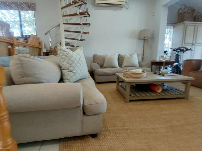 Spacious living area featuring a distinctive spiral staircase and wall-mounted air conditioning unit, offering a comfortable and functional layout.