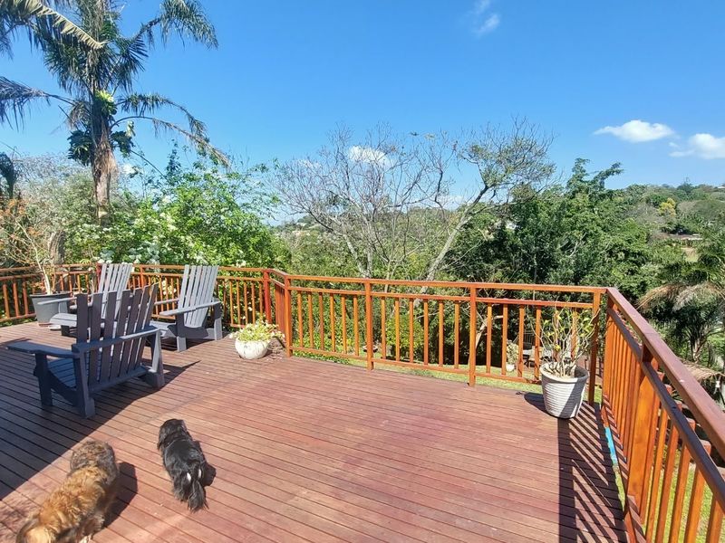 Spacious elevated timber deck featuring a wooden balustrade and scenic views of the surrounding garden and lush landscape.