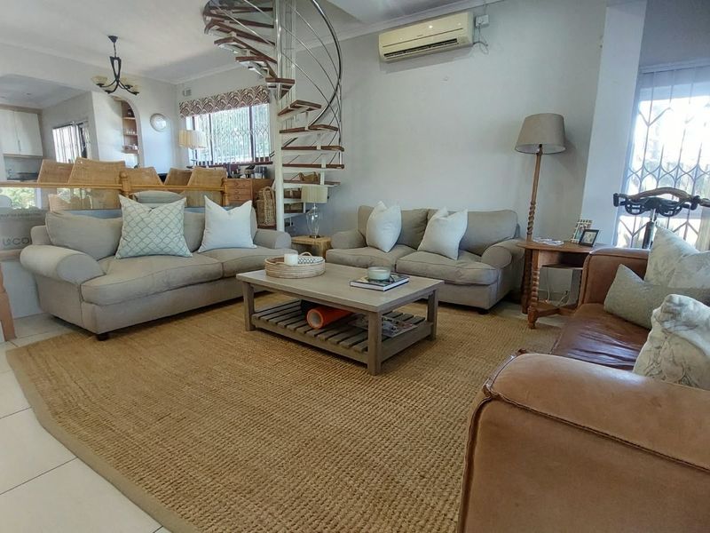 Spacious open-plan living area featuring a distinctive spiral staircase, tiled flooring, and a wall-mounted air conditioning unit.