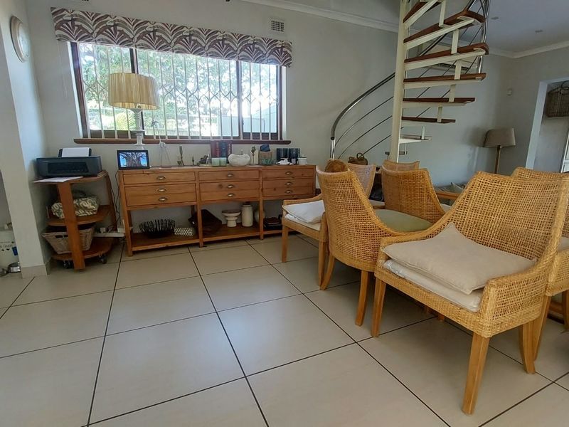 Open plan living area featuring tiled flooring and a modern spiral staircase leading to the upper level.