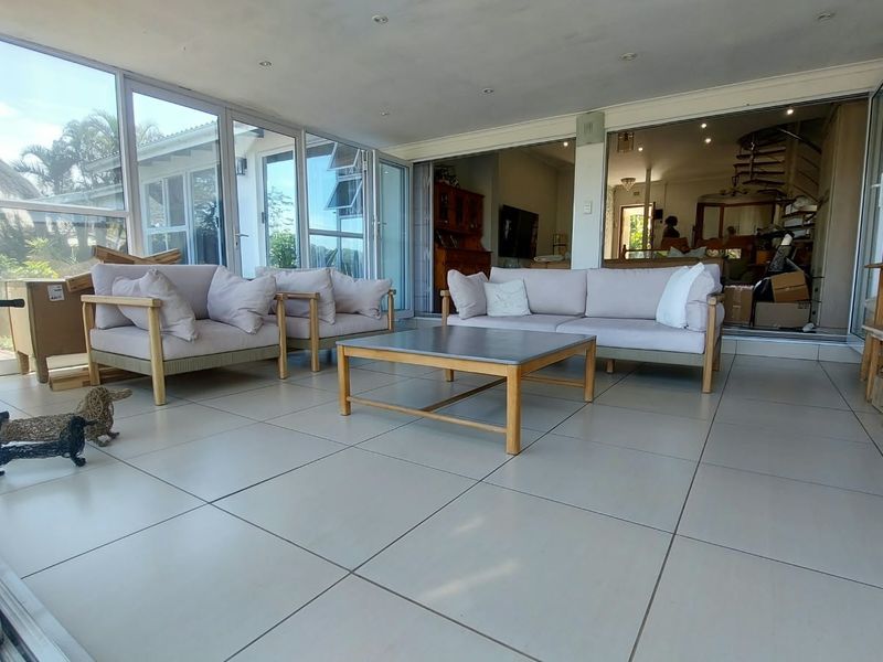Spacious enclosed patio featuring large aluminium stacking doors, neutral floor tiles, and recessed lighting, offering a seamless transition to the outdoor area.