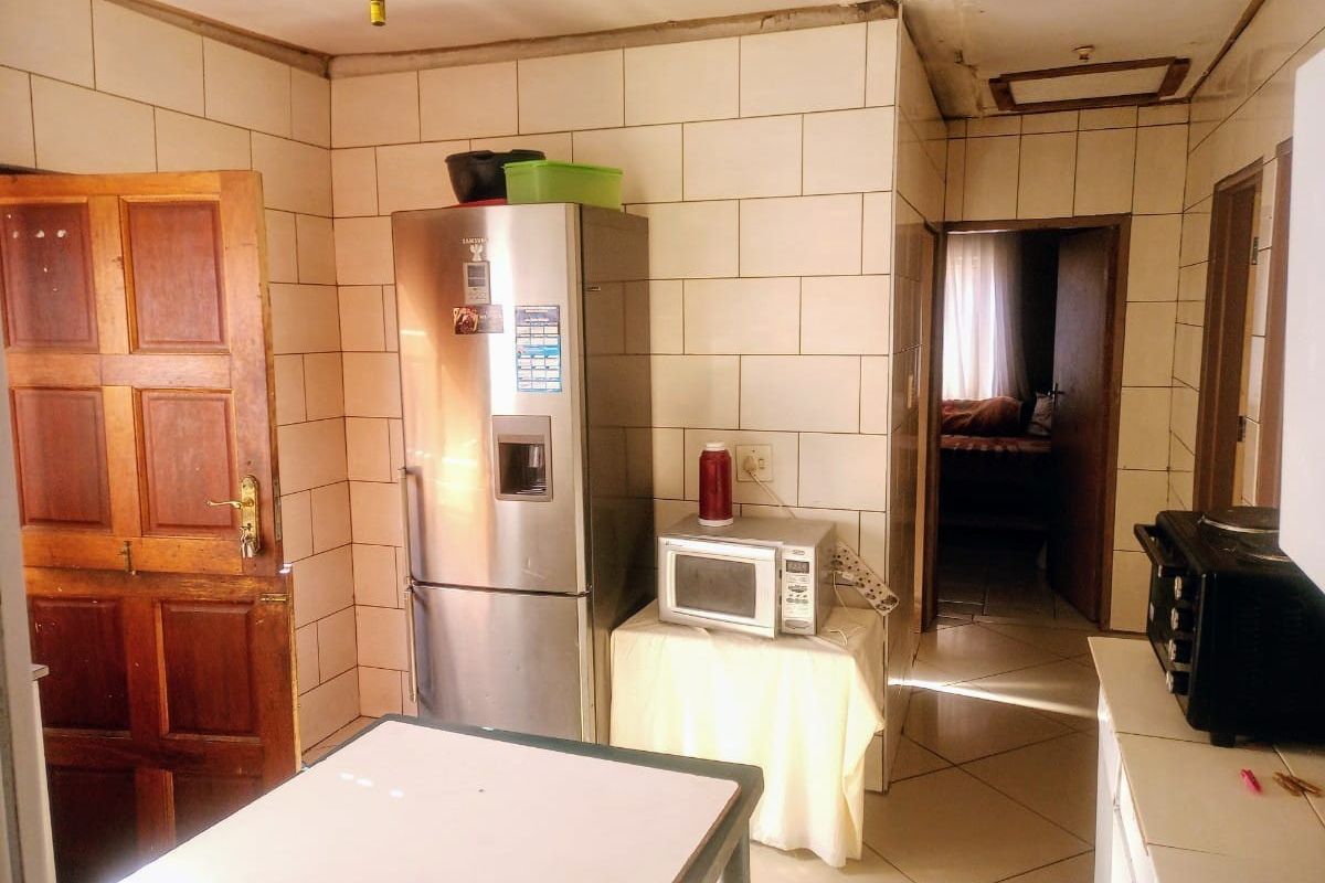 A dated kitchen area featuring tiled walls and flooring, requiring significant renovation and repair to the ceiling and finishes.
