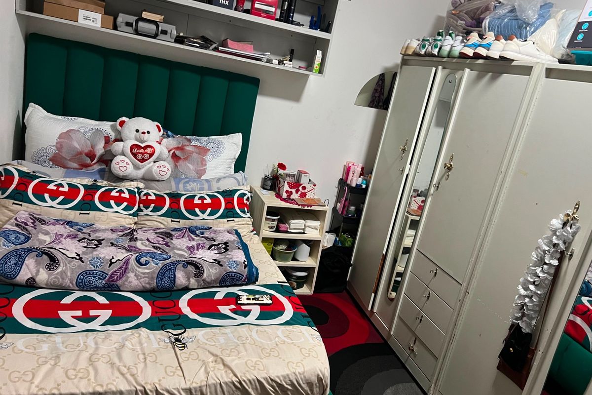 A bedroom featuring a built-in wardrobe with mirrored panels and overhead shelving for storage.