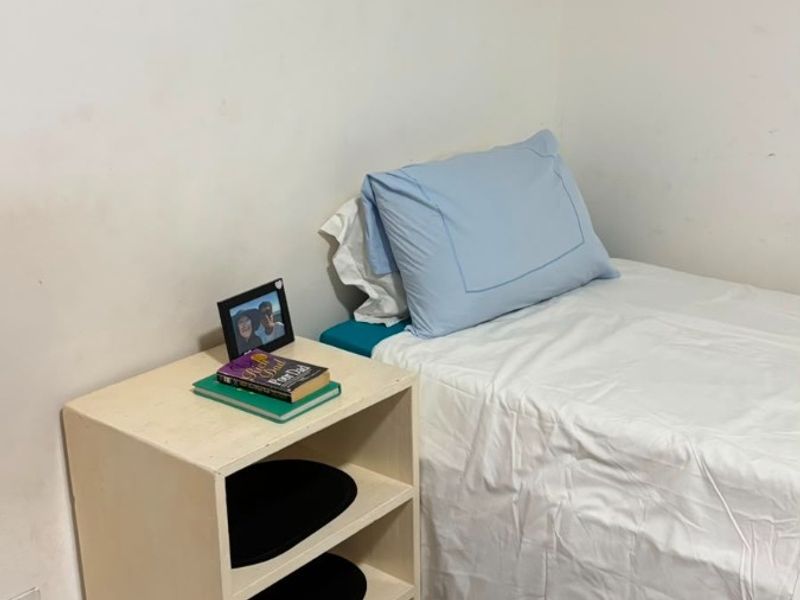 A compact bedroom featuring tiled flooring and built-in wall shelving, requiring minor cosmetic updates to the wall finishes.