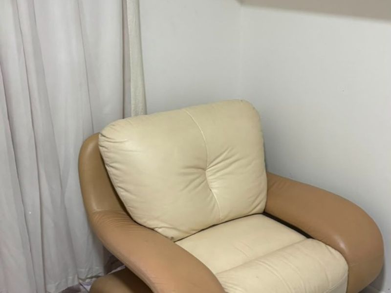 A small living area featuring tiled flooring and a wall-mounted shelving unit, currently showing signs of wear and dated finishes.