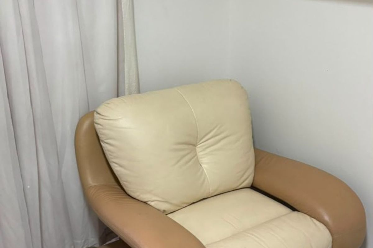 A small living area featuring tiled flooring and a wall-mounted shelving unit, currently showing signs of wear and dated finishes.