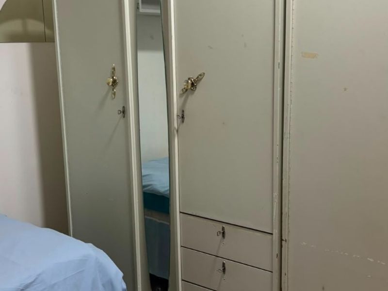 Bedroom featuring a large built-in wardrobe with integrated mirror and drawers, complemented by tiled flooring.
