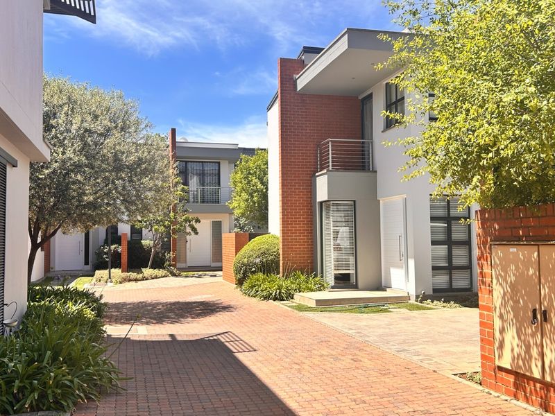 A view of the townhouse complex featuring modern brick and rendered facades, paved driveways, and established landscaping.