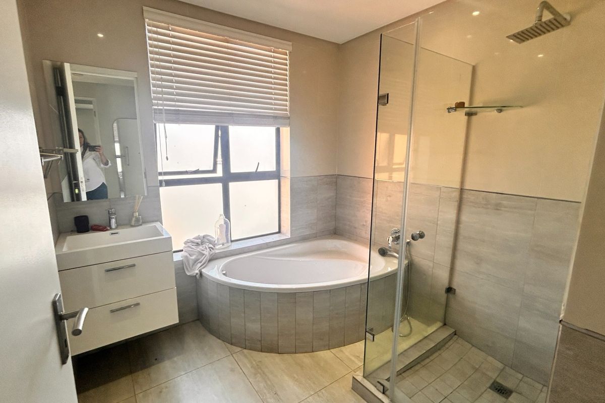 Modern bathroom featuring a built-in vanity, a tiled drop-in bathtub, and a separate glass-enclosed shower with a rain shower head.