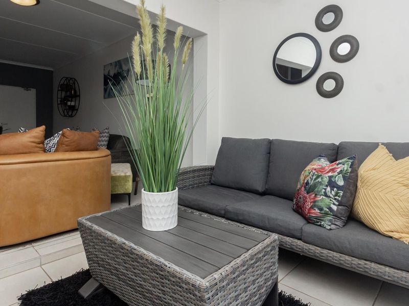 An open-plan living area featuring neutral tiled flooring and modern recessed ceiling lighting, creating a bright and cohesive space for relaxation.