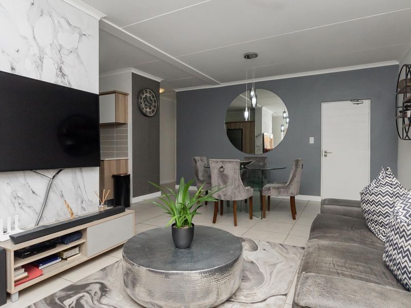 Modern open-plan living and dining area featuring a striking marble-effect feature wall, neutral tiled flooring, and contemporary finishes throughout.