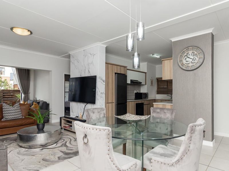 Modern open-plan living and dining area featuring a marble-look feature wall, sleek kitchen cabinetry, and contemporary tiled flooring throughout.