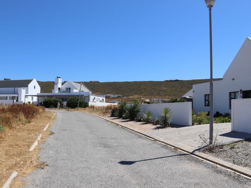 A view of the residential street showing paved road access, street lighting, and surrounding properties with boundary walls.