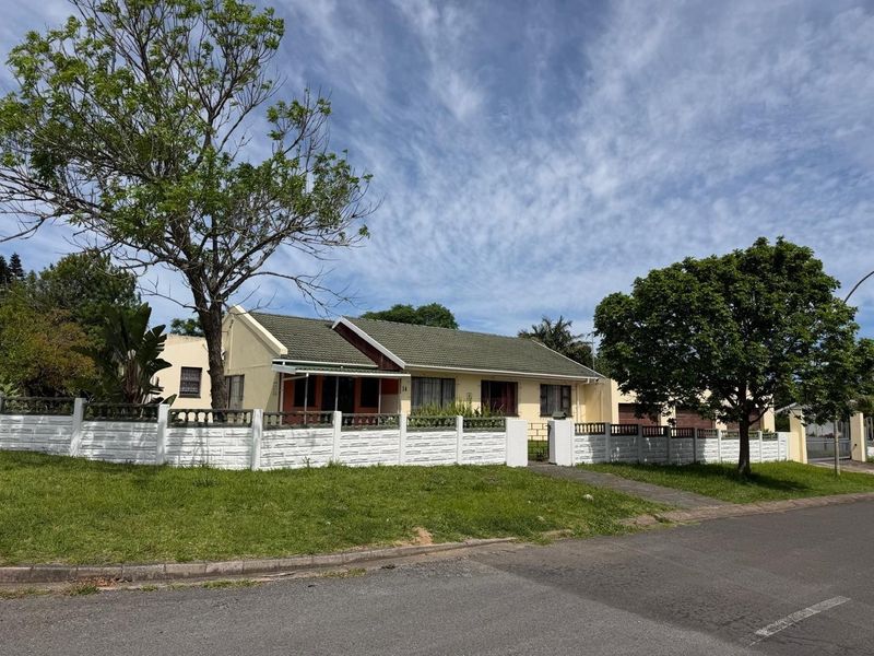 Front elevation of a single-story house featuring a tiled roof, paved driveway, and a secure precast concrete boundary wall.