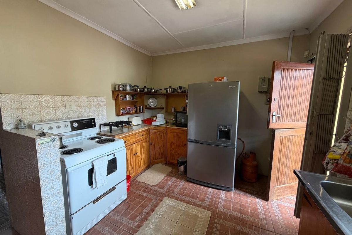 A functional kitchen featuring wooden cabinetry, tiled splashbacks, and a freestanding stove, with direct access to the exterior via a stable door.