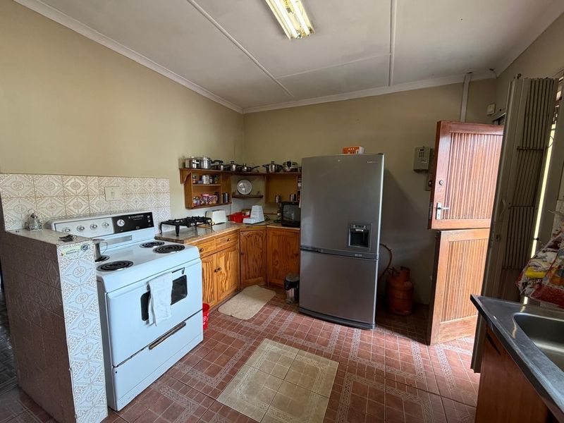 A functional kitchen featuring wooden cabinetry, tiled splashbacks, and a freestanding stove, with direct access to the exterior via a stable door.