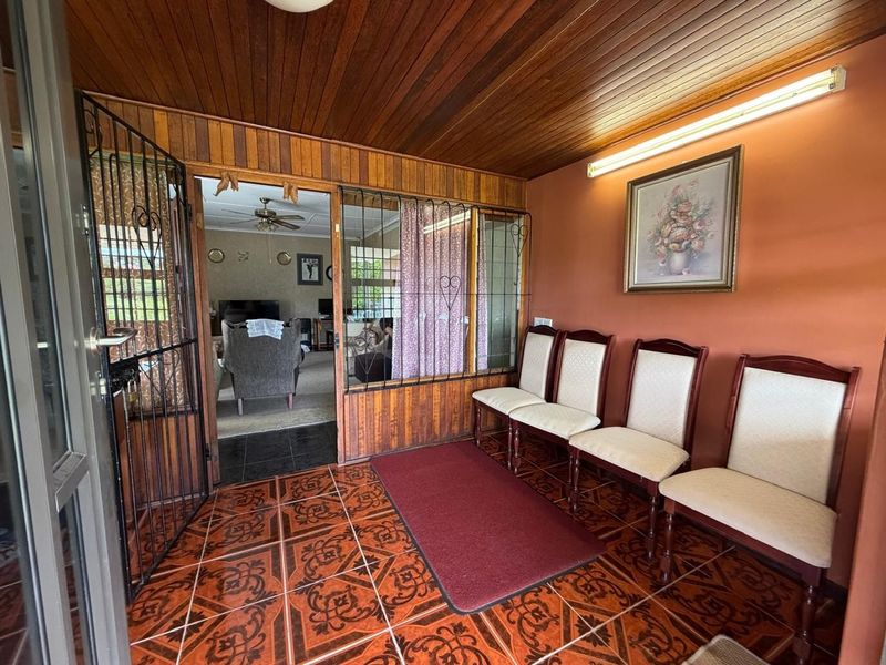 Entrance foyer featuring timber-paneled ceilings, patterned ceramic floor tiles, and a security gate leading into the main living area.