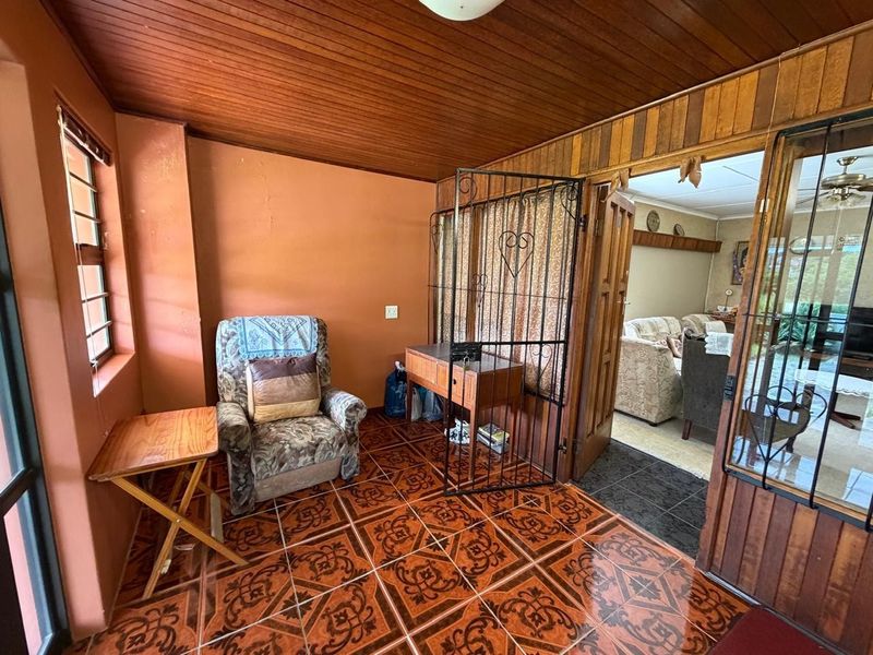 An entrance area featuring a wooden ceiling and patterned ceramic floor tiles, leading into the main living space through a security gate.