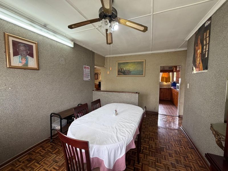 Dining room featuring traditional parquet flooring, a ceiling fan, and a pass-through opening connecting to the kitchen area.