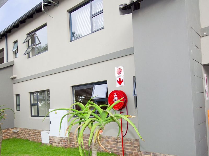 A view of the apartment building exterior featuring modern grey facade, aluminium windows, and installed fire safety equipment including a hose reel and extinguisher.