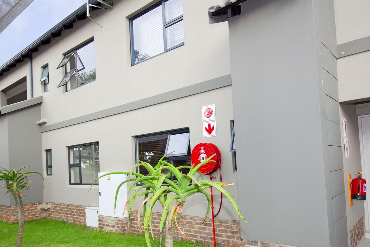 A view of the apartment building exterior featuring modern grey facade, aluminium windows, and installed fire safety equipment including a hose reel and extinguisher.