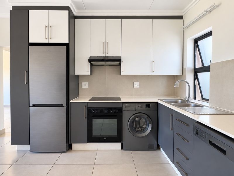 Modern kitchen featuring sleek two-tone cabinetry, stone countertops, integrated appliances, and high-quality tiled finishes in a clean, contemporary layout.