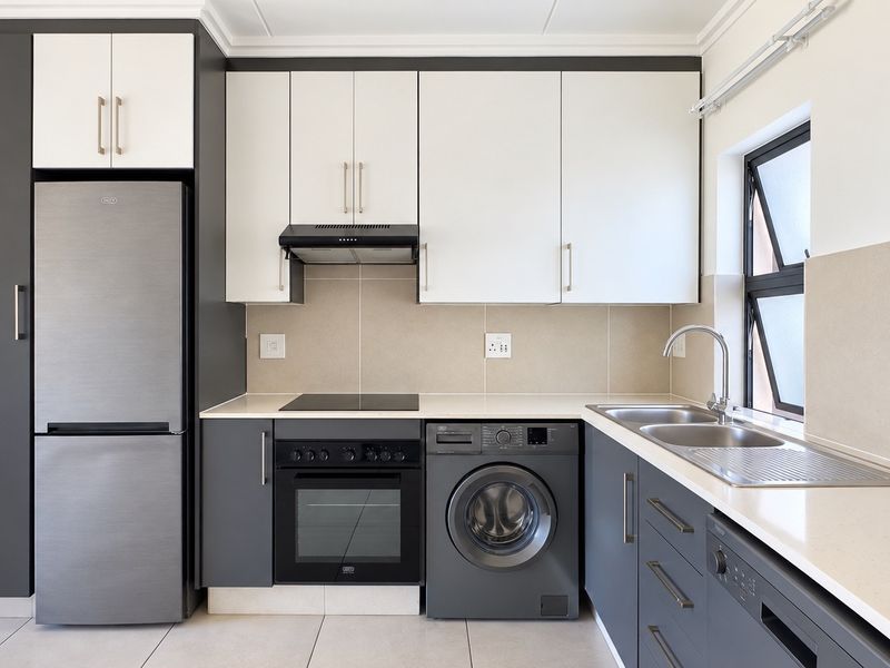 Modern kitchen featuring sleek two-tone cabinetry, stone countertops, integrated appliances, and a stainless steel double sink with a tiled splashback.