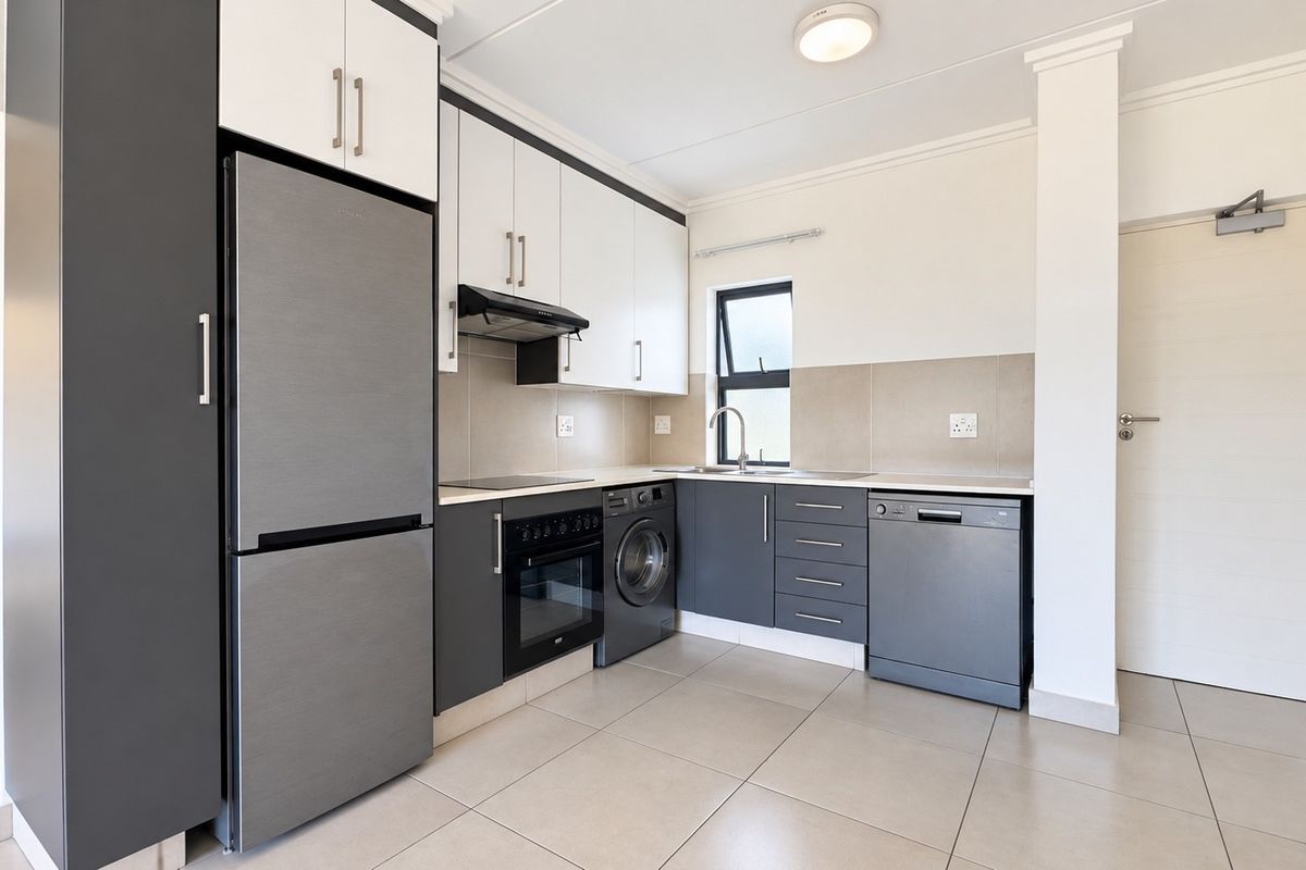Modern kitchen featuring two-tone cabinetry, integrated oven, extractor fan, stainless steel sink, and tiled flooring with a neutral backsplash.