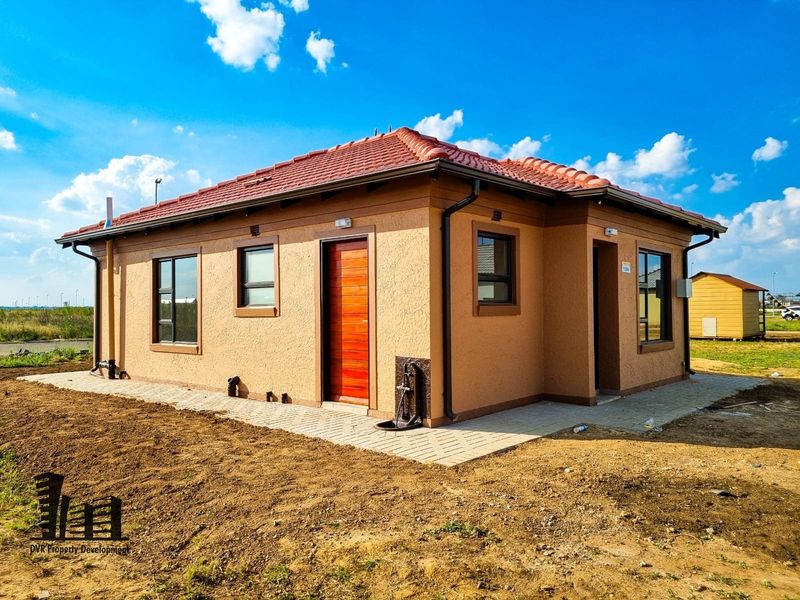Rear view of a modern single-story house featuring a tiled roof, textured plaster finish, and paved perimeter walkway.