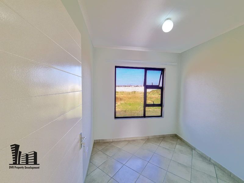 A clean, empty bedroom featuring neutral tiled flooring, a modern aluminium window frame, and a white internal door, ready for personalization.