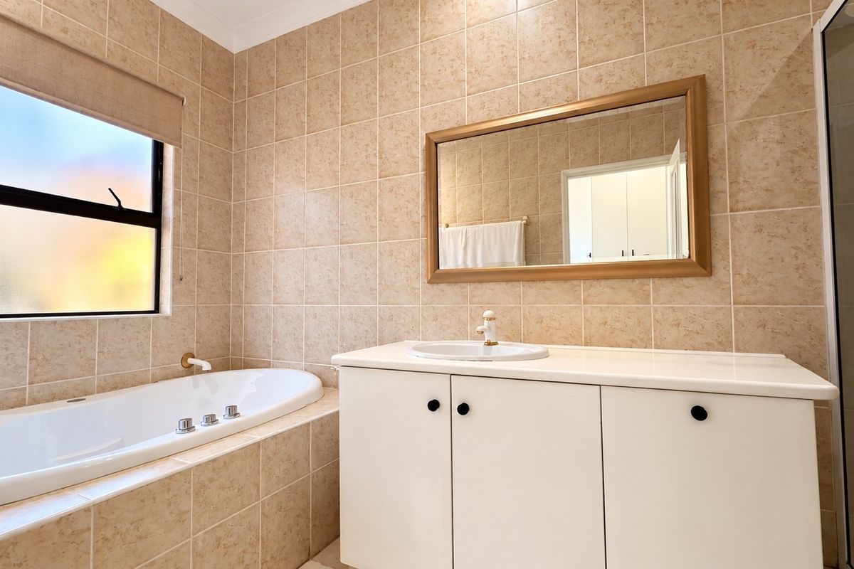 A functional bathroom featuring a built-in bathtub, a vanity cabinet with a basin, and tiled wall finishes.